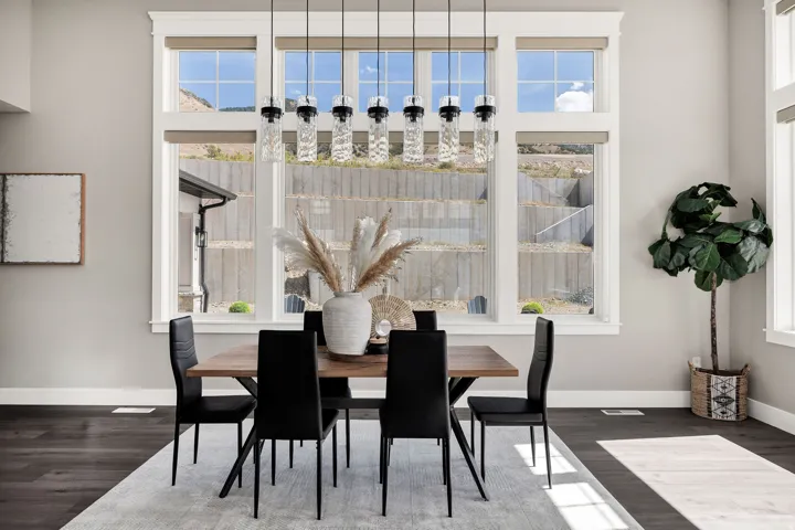 Expansive window array, contemporary chandelier with multiple pendants, rich wood-finish flooring, and neutral wall tones