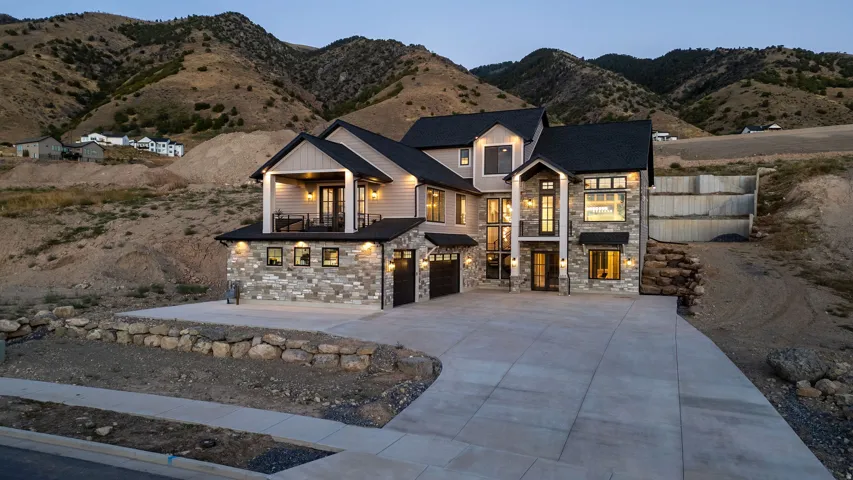Two-story residence featuring stone and siding exterior, multi-car concrete driveway, and covered balcony