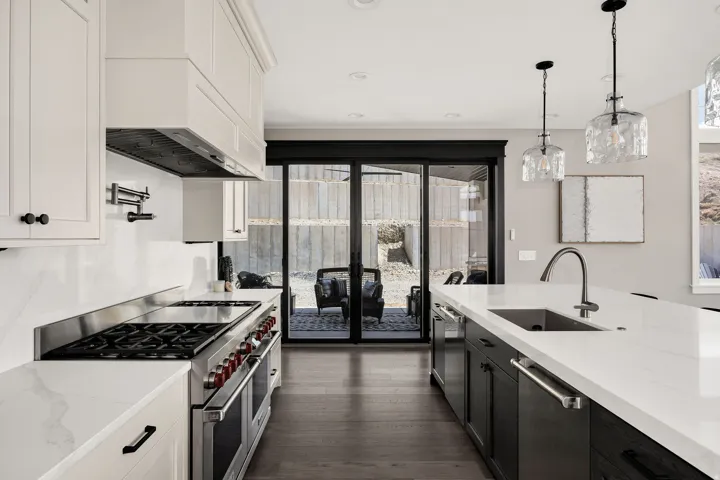 Gourmet kitchen featuring a stainless steel range, white shaker cabinetry, quartz countertops, and a pot filler