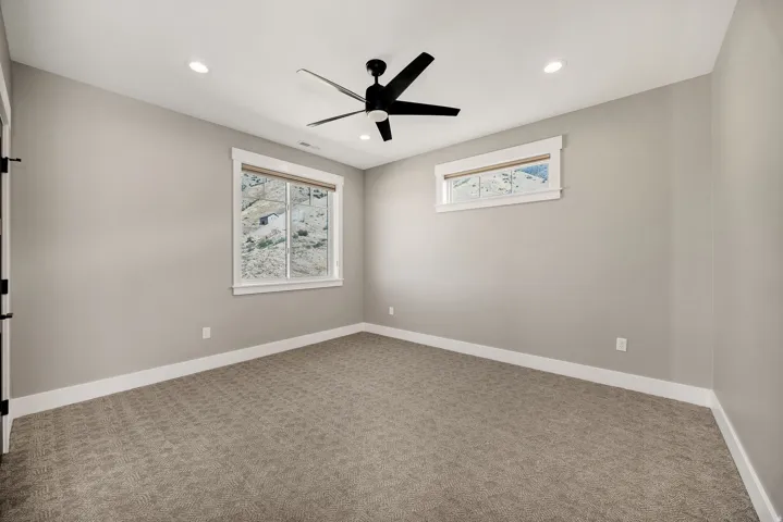 Recessed lighting, ceiling fan, neutral wall paint, white trim, carpet flooring