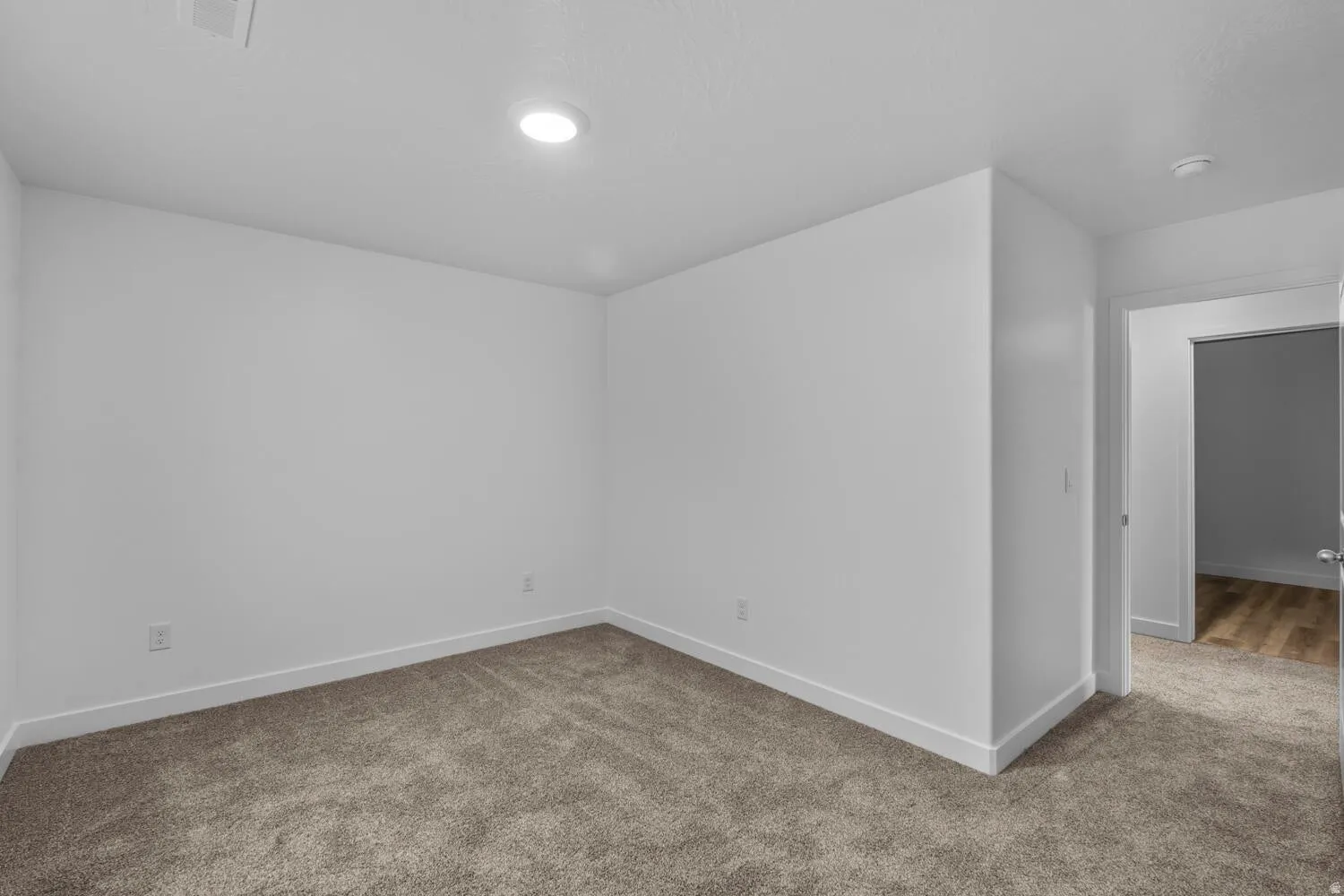 Recessed lighting, white walls, and neutral carpeting