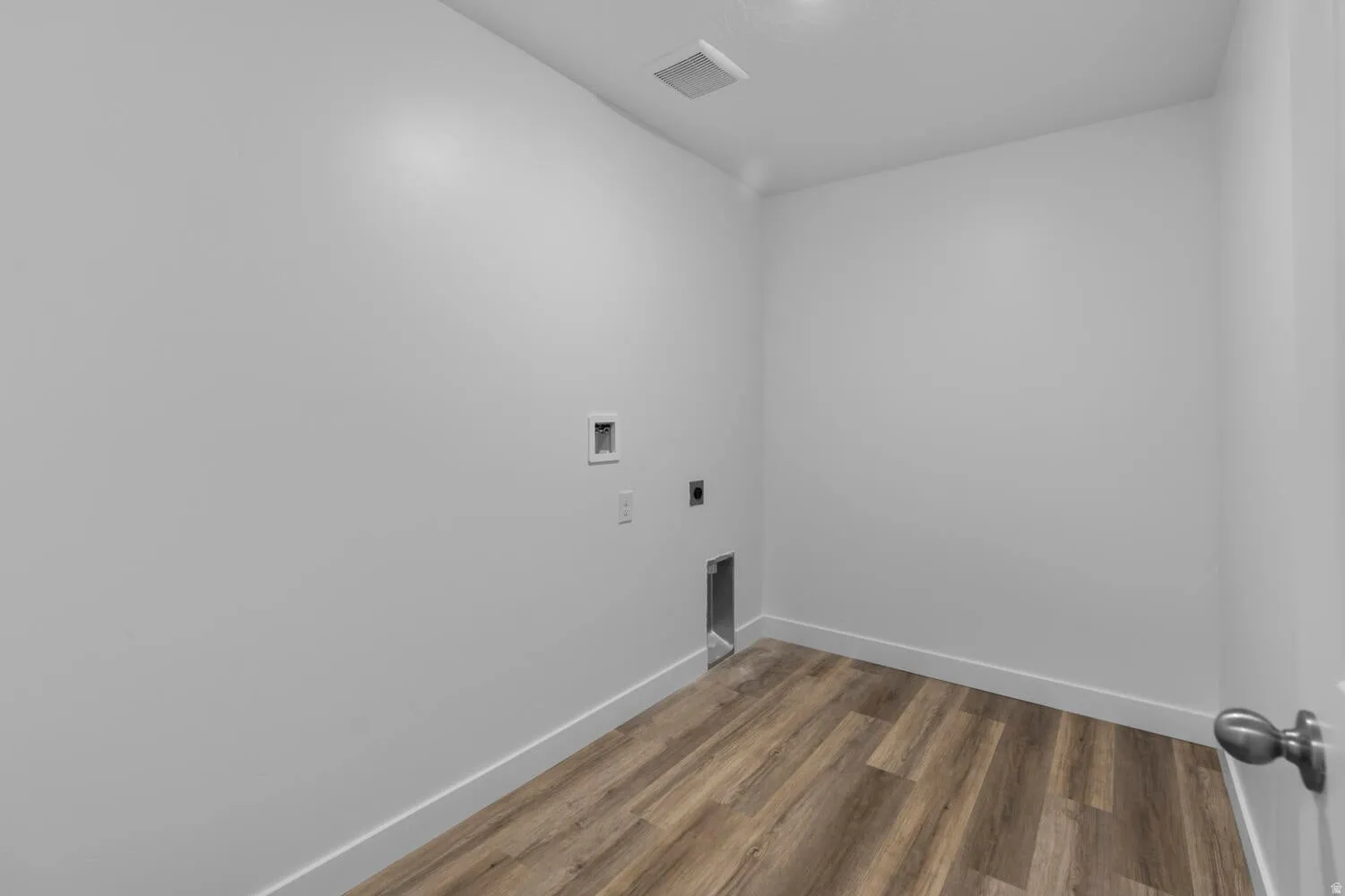 Dedicated laundry space with wood-finish flooring, white walls, and pre-installed utility connections