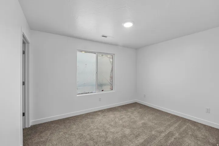 Recessed lighting, white walls, gray carpet flooring, and a white window frame