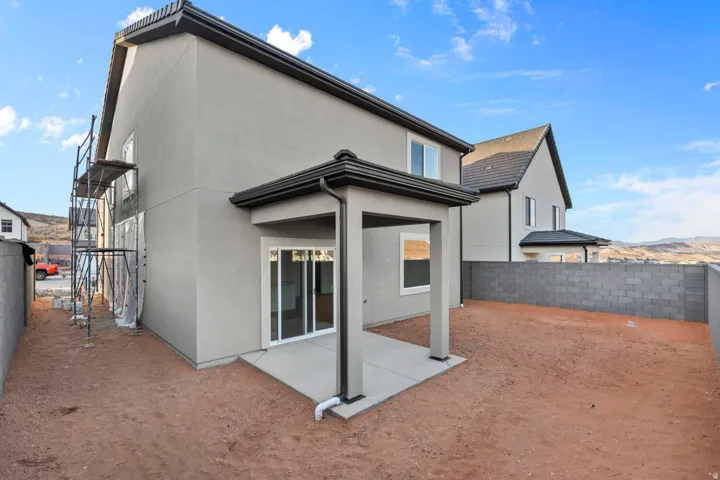 Rear exterior featuring a covered patio, sliding glass doors, and a block wall perimeter