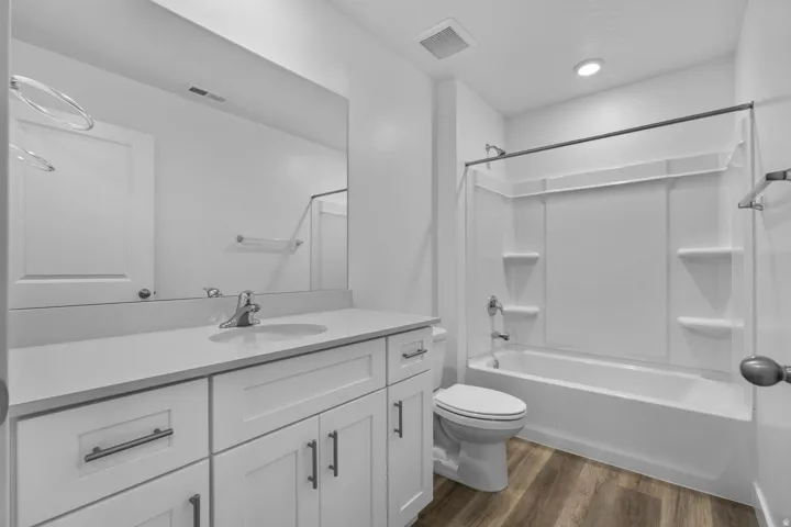White vanity with a single basin sink, white countertop, and brushed nickel faucet