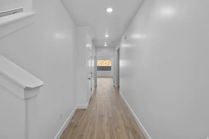 Hallway with wood-finish flooring, recessed lighting, and white baseboards