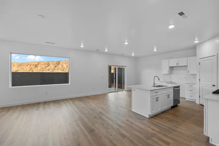 Open-concept living space featuring wood-finish flooring, recessed lighting, and a sliding glass door
