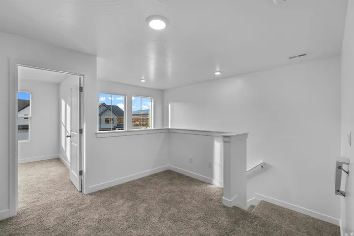 Carpeted landing with white balustrade, multiple windows, recessed lighting, and white trim throughout