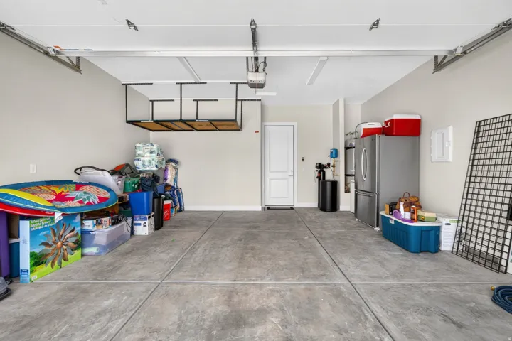 Concrete flooring, overhead storage rack, white door, and built-in wall panel