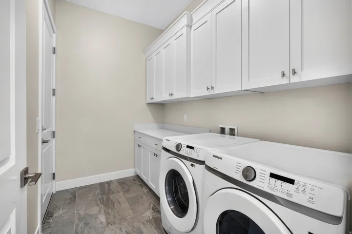 Upper and lower cabinetry with modern hardware, stone-finish countertop, and durable tile flooring