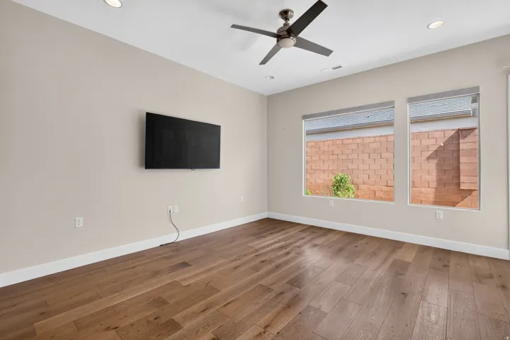 Wood-finish flooring, recessed lighting, ceiling fan, and two large windows