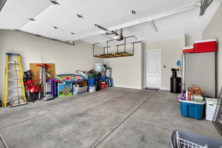 Spacious garage with a concrete floor, built-in overhead storage, and an interior access door