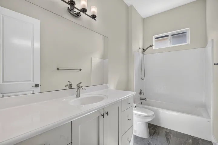 White vanity with a solid surface countertop, undermount sink, and chrome faucet
