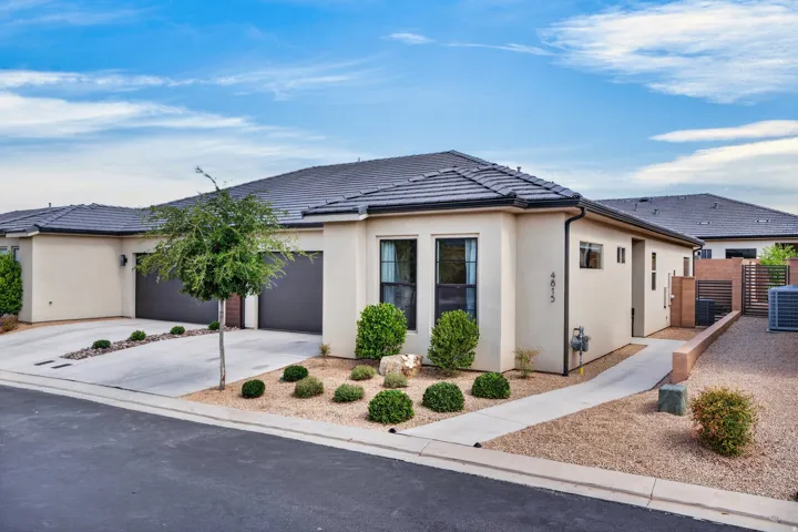Stucco exterior with a tiled roof, featuring an attached two-car garage and a concrete driveway