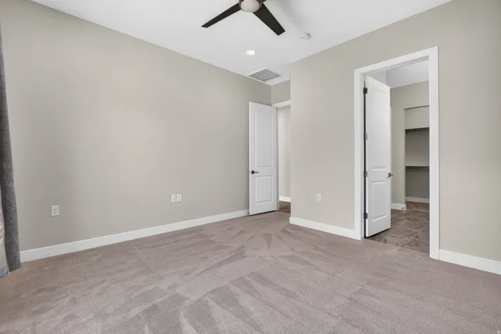 Neutral wall color, ceiling fan, recessed lighting, carpeted flooring, and a walk-in closet with shelving
