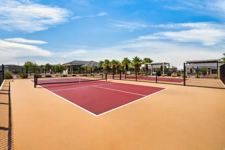 Multiple sports courts featuring red playing surfaces and perimeter fencing