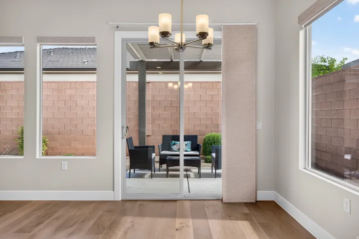 Wood-finish flooring with a multi-pane sliding glass door, recessed lighting, and a contemporary chandelier
