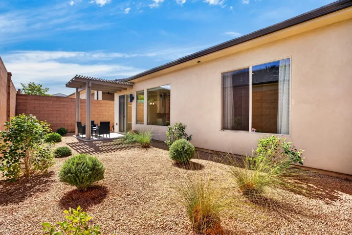 Rear exterior featuring a stucco finish, multiple large windows, and a covered patio with a slatted pergola