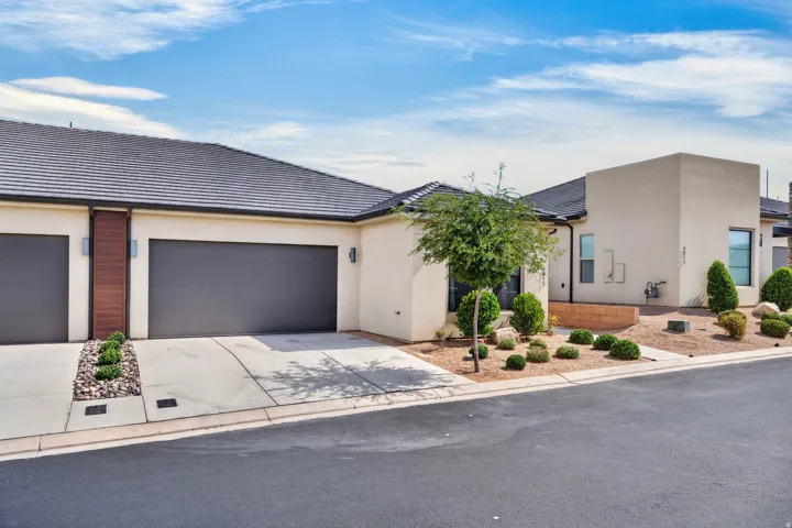 Contemporary exterior with stucco finish, dark tiled roof, and integrated garage doors