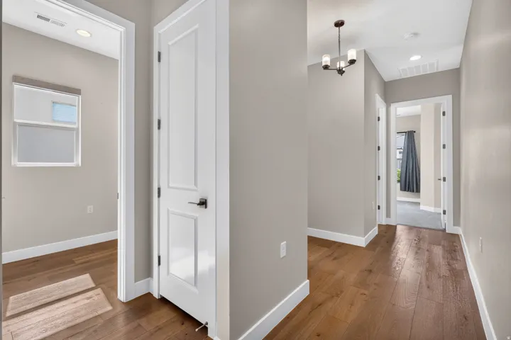 Wood-finish flooring, recessed ceiling lighting, crisp white trim, and a contemporary chandelier