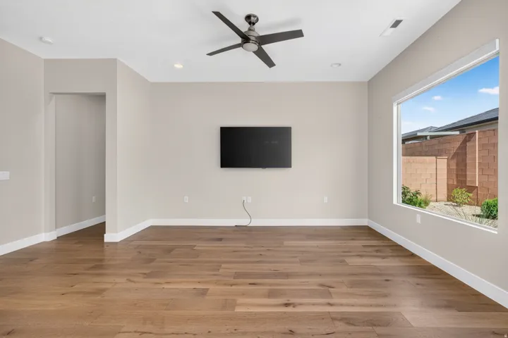 Spacious living area featuring wood-finish flooring, a contemporary ceiling fan, recessed lighting, and a large picture window