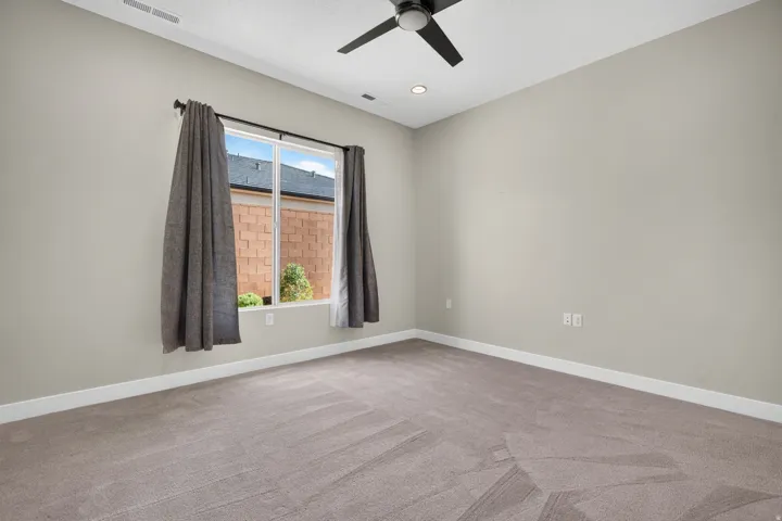 Neutral tone walls with white trim, a large window, a ceiling fan with integrated lighting, and recessed ceiling lighting