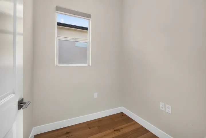 Wood-finish flooring, white trim, and a window with roller shade