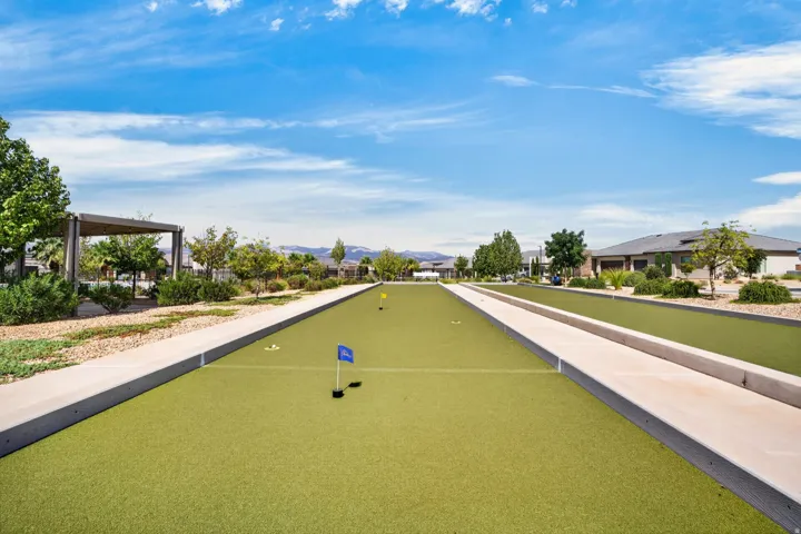 Manicured putting green with multiple holes, bordered by concrete pathways and low-maintenance landscaping