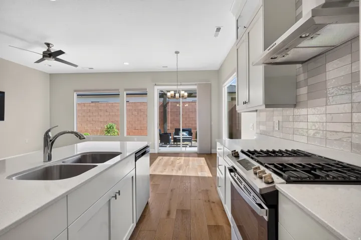 Kitchen featuring light-toned cabinetry, stainless steel appliances, a gas range, and a dual basin sink