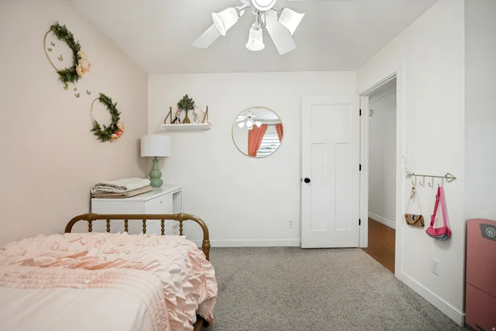 Textured carpeting, a ceiling fan with integrated lighting, and a white panel door with black hardware