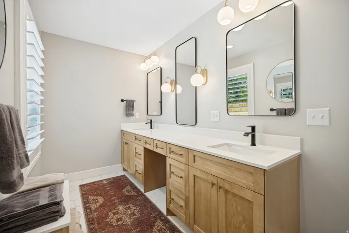 Dual undermount sinks with matte black fixtures, light wood-finish cabinetry, and white countertops