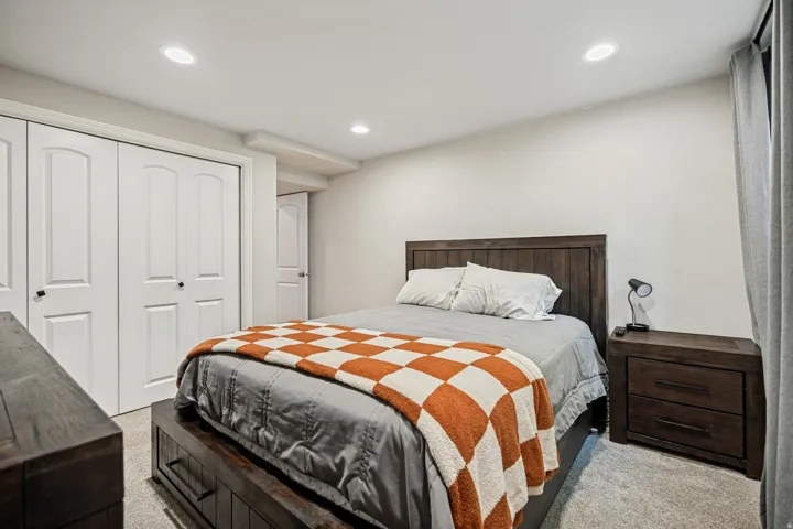 White bi-fold closet doors, recessed ceiling lighting, and soft gray carpeting