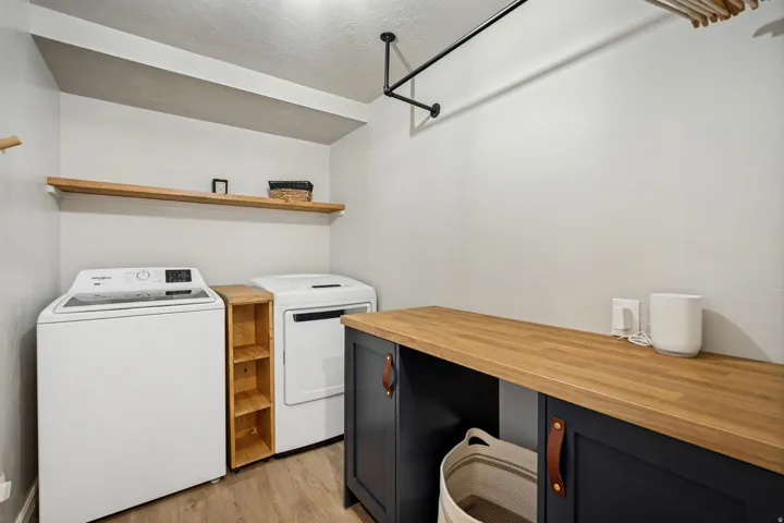 Laundry area featuring a wood-finish countertop, dark cabinetry, and a wall-mounted hanging rod