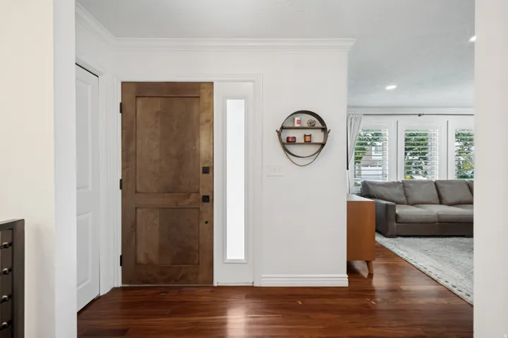 Wood-finish flooring throughout, solid wood entry door, and a vertical frosted glass sidelight