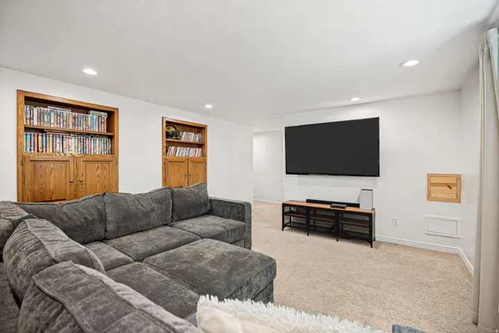 Recessed lighting, light-toned carpeting, and two built-in wood-finish shelving units with cabinetry