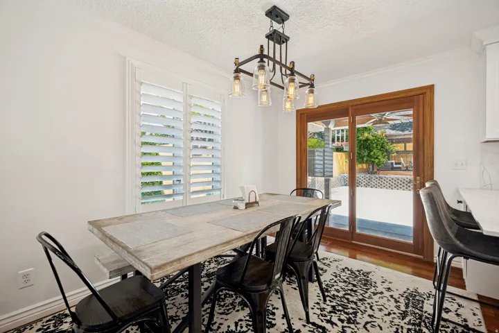 White plantation shutters, crown molding, wood-finish flooring, and a modern chandelier