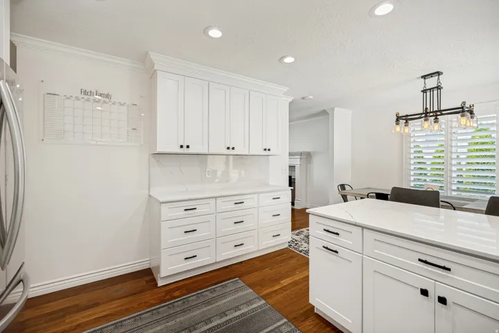 White cabinetry, wood-finish flooring, recessed lighting, white countertops, and window shutters