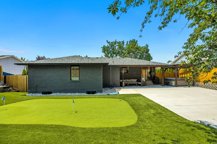 Expansive backyard featuring a putting green, a concrete patio, and an attached covered patio with a pergola