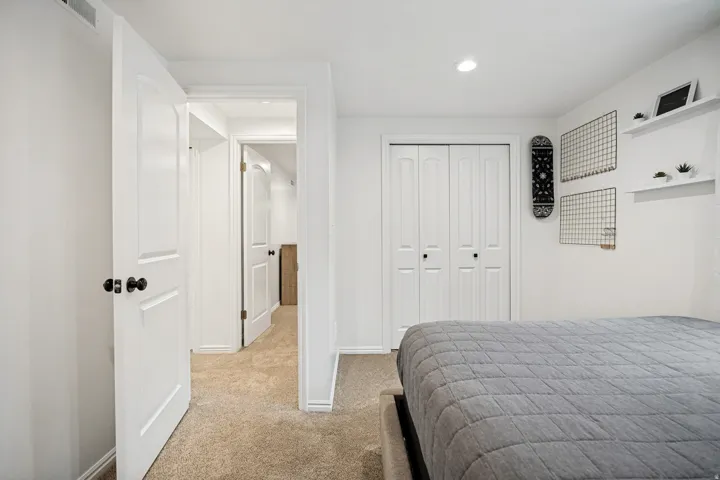 Neutral wall paint, recessed ceiling lighting, textured carpet flooring, bi-fold closet doors, and panel-style interior doors
