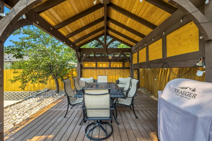 Covered outdoor deck with a wood-finish ceiling, exposed beams, wood-finish flooring, and a privacy fence