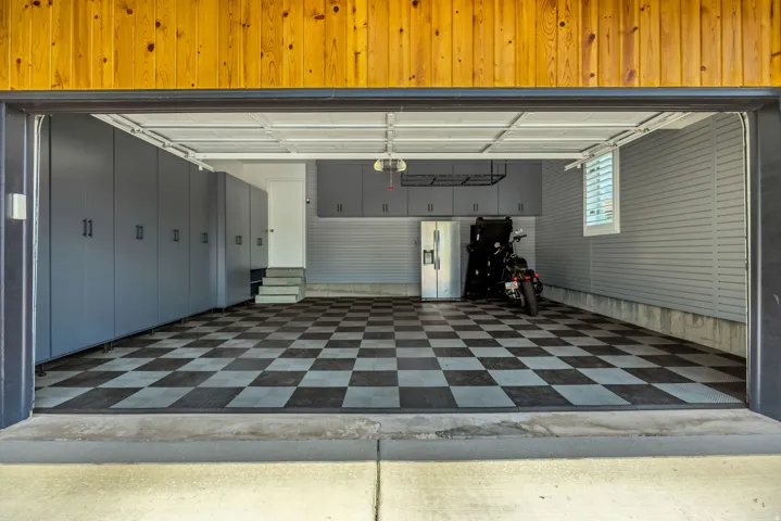 Garage with checkered flooring, extensive built-in cabinetry, and wall-mounted storage racks