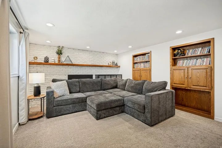 Recessed lighting illuminates the space, featuring a white painted brick accent wall with a wood mantel