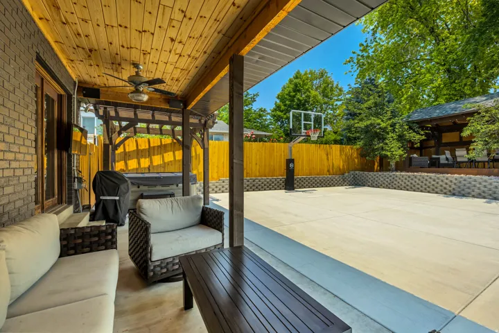 Covered patio with a wood-finish ceiling, ceiling fan, and brick exterior wall