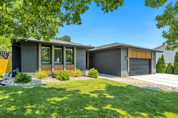 Modern exterior featuring dark brick, wood paneling, a concrete driveway, and a two-car garage