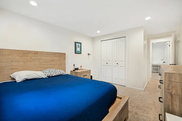 Recessed lighting illuminates the room, featuring light-toned walls and carpet flooring