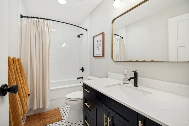 Bathroom featuring a tiled tub-shower combination, a vanity with an integrated sink and stone countertop, and hexagon tile flooring