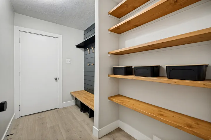 Built-in wooden shelving, integrated wooden bench, wall-mounted coat hooks, and durable flooring