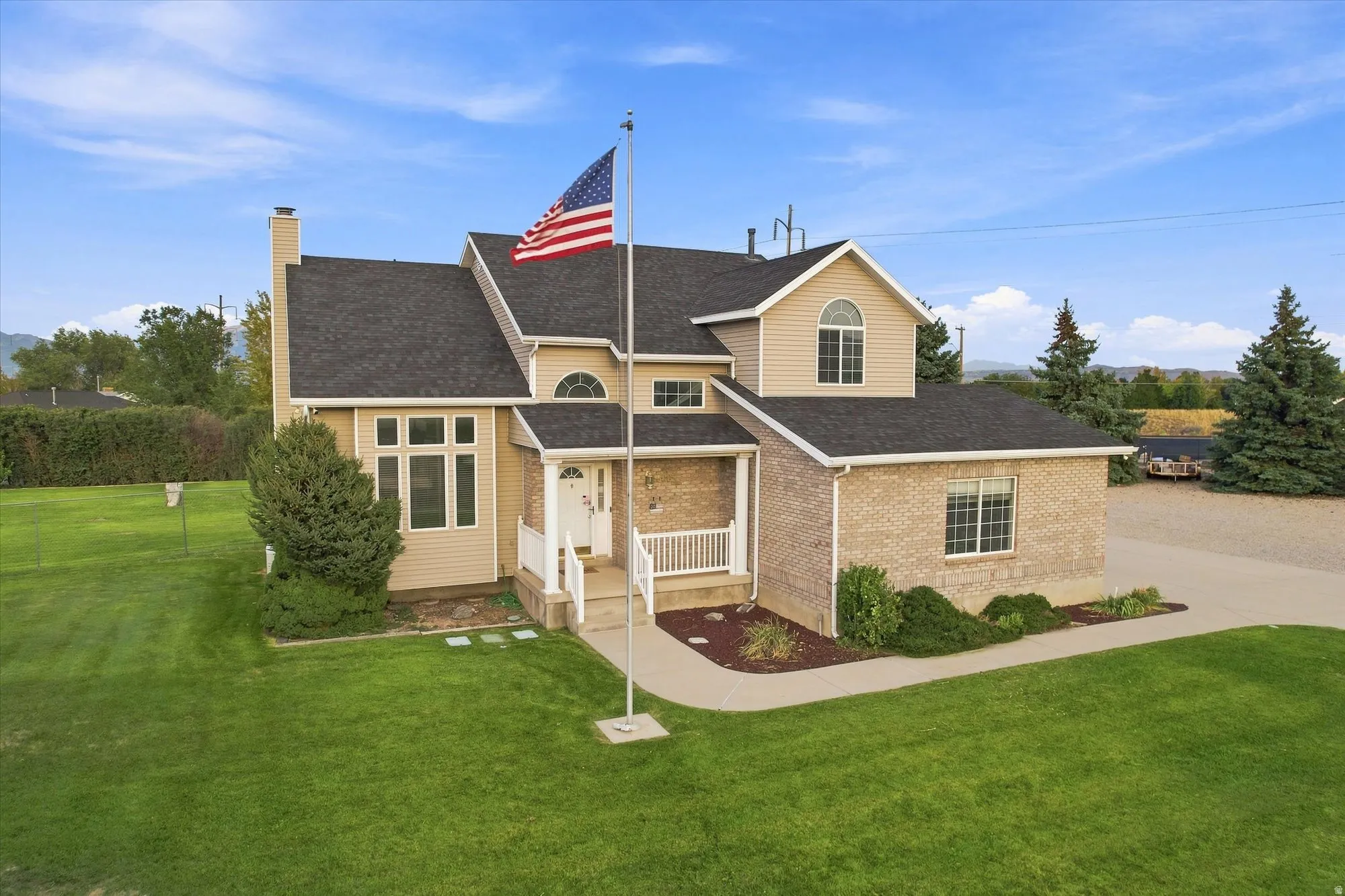 Two-story residence featuring a brick and siding exterior, front porch with white railing, and a flag pole