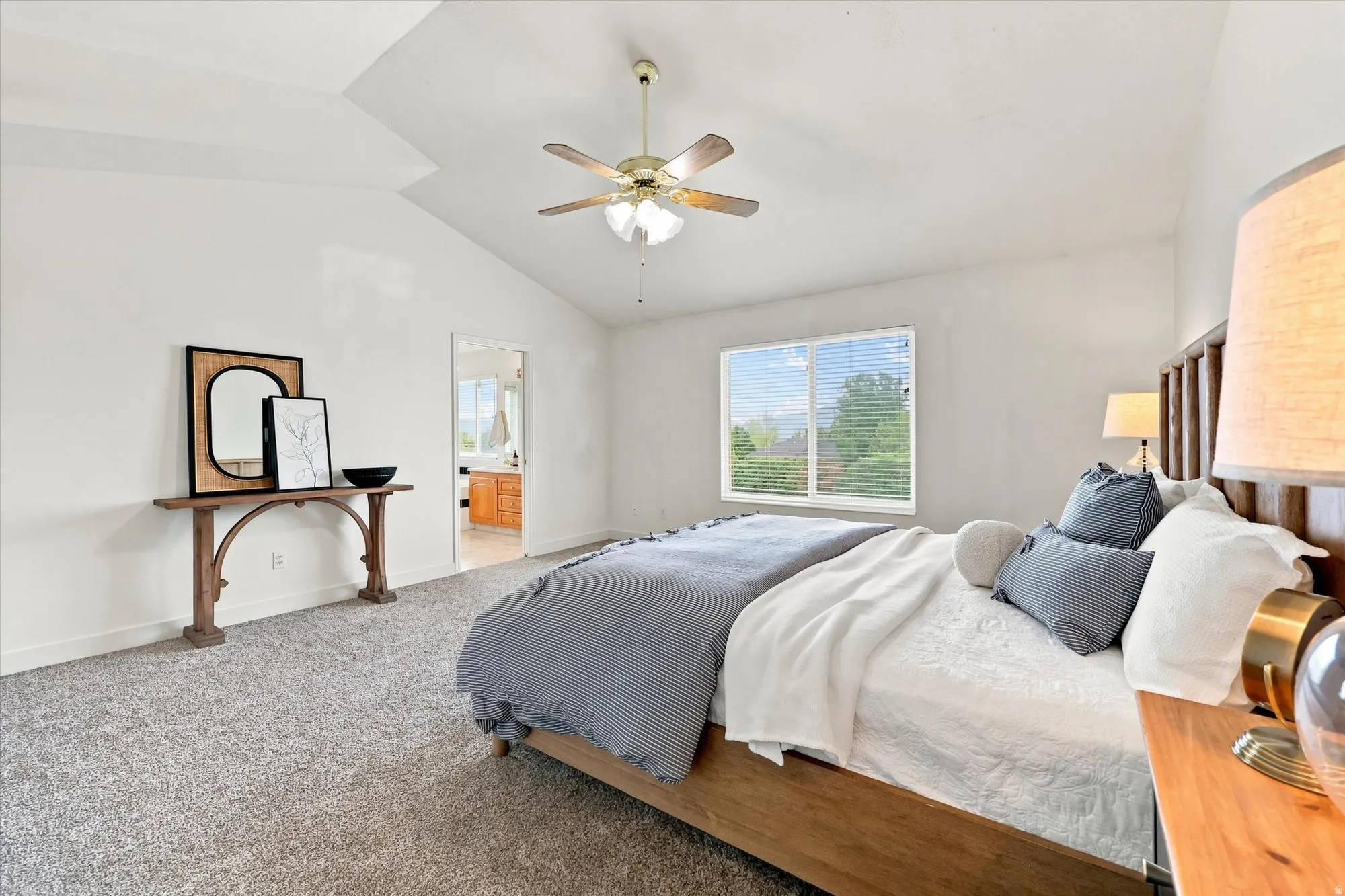 Vaulted ceiling with a ceiling fan, light-toned carpet, and a window with horizontal blinds