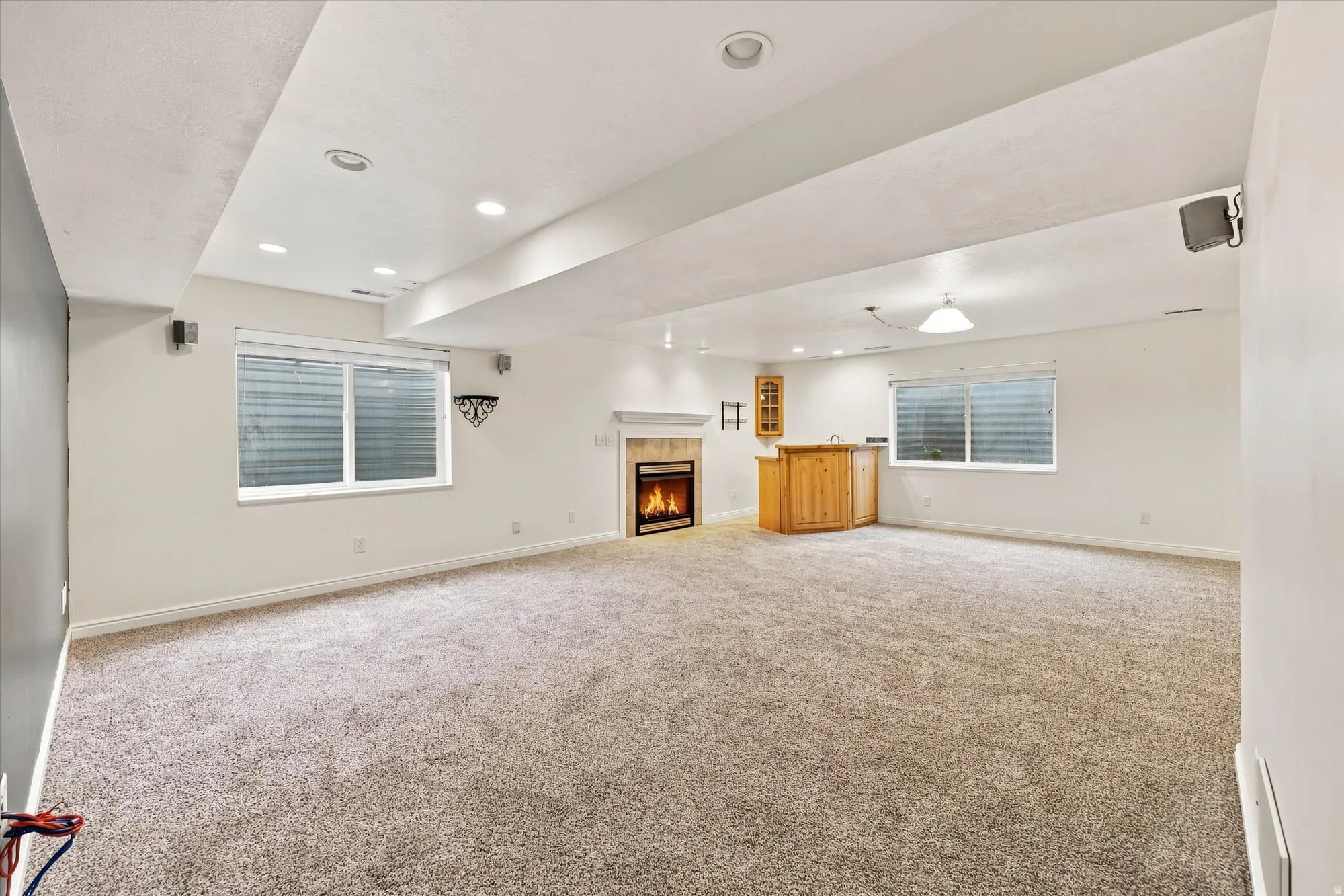 Recessed lighting, wood-finish wet bar, built-in cabinetry, fireplace with mantel, and carpeted flooring